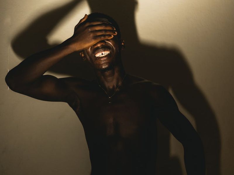 Man in a dynamic yoga pose against a dark background.
